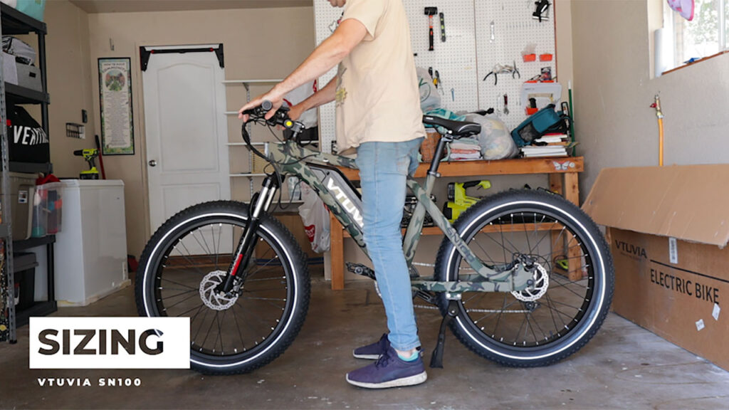 Man standing over the Vtuvia SN100 fat tire e-bike.